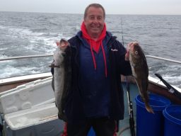 Angler holding up a Pollack and a Codling